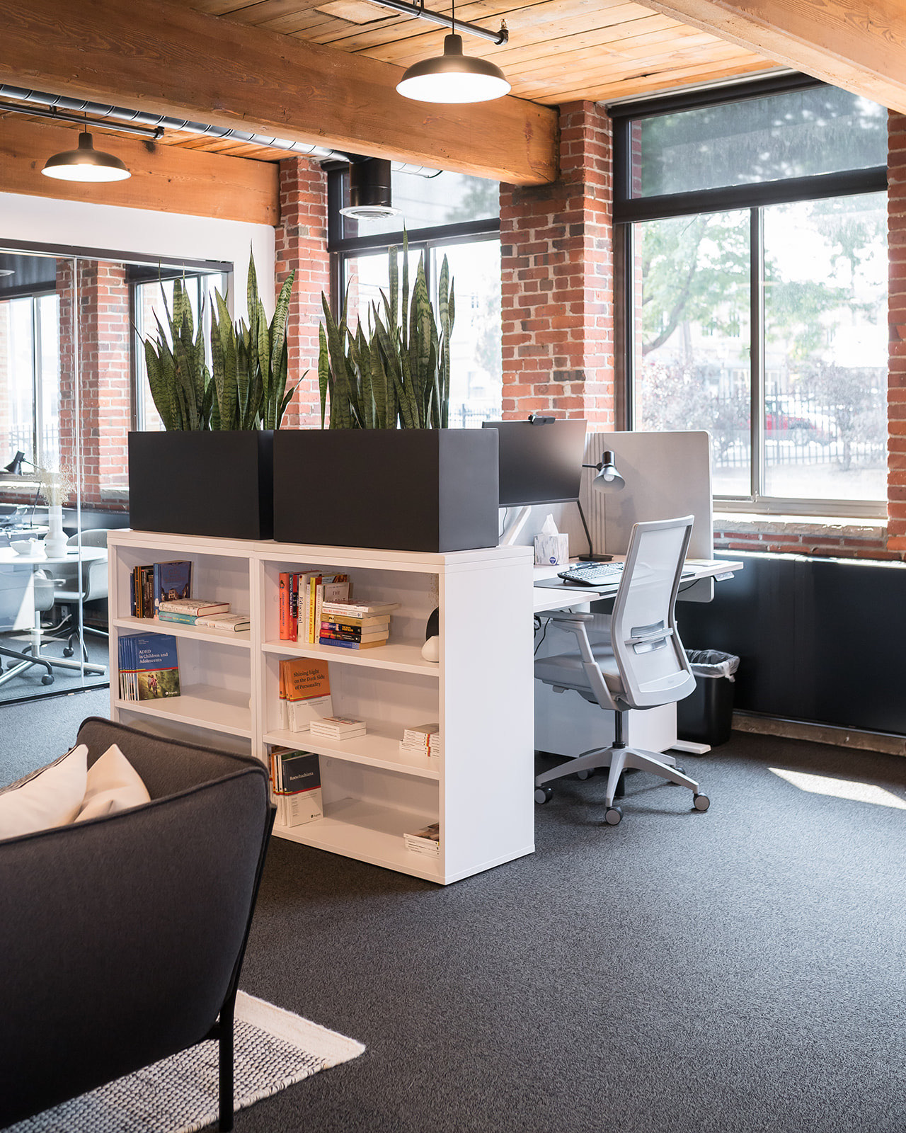 Workstations and library shelving beside a glass-walled conference room